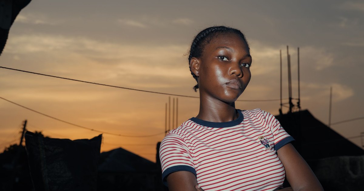 A young woman holding a smartphone showing social media apps in dim light