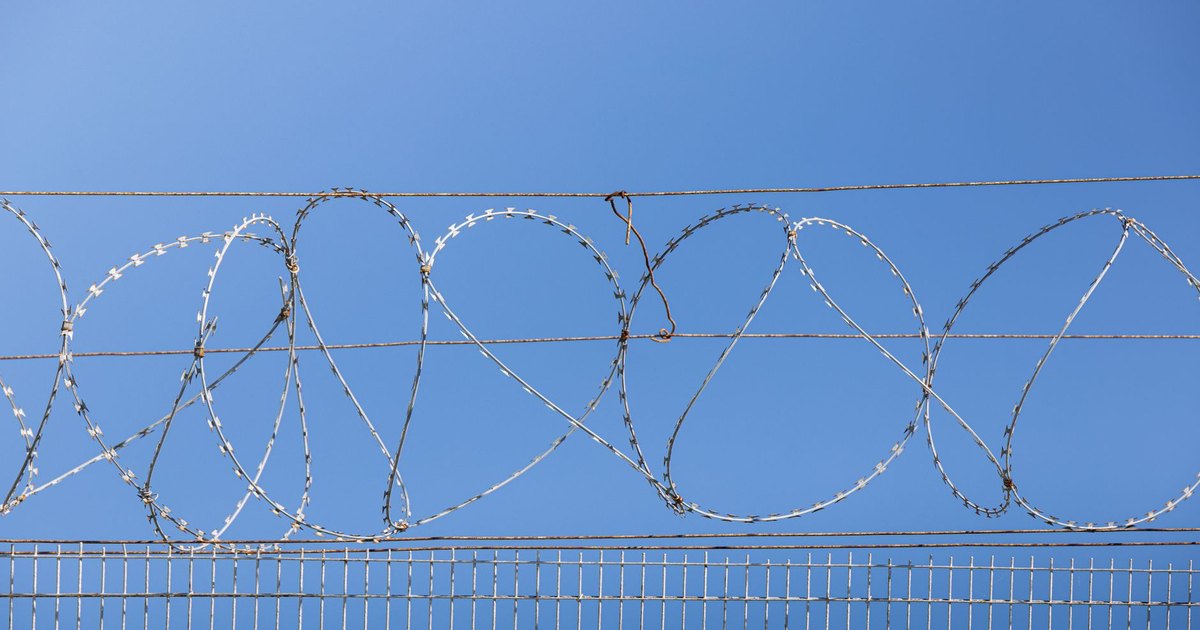 A razor-wire border fence along a coastline